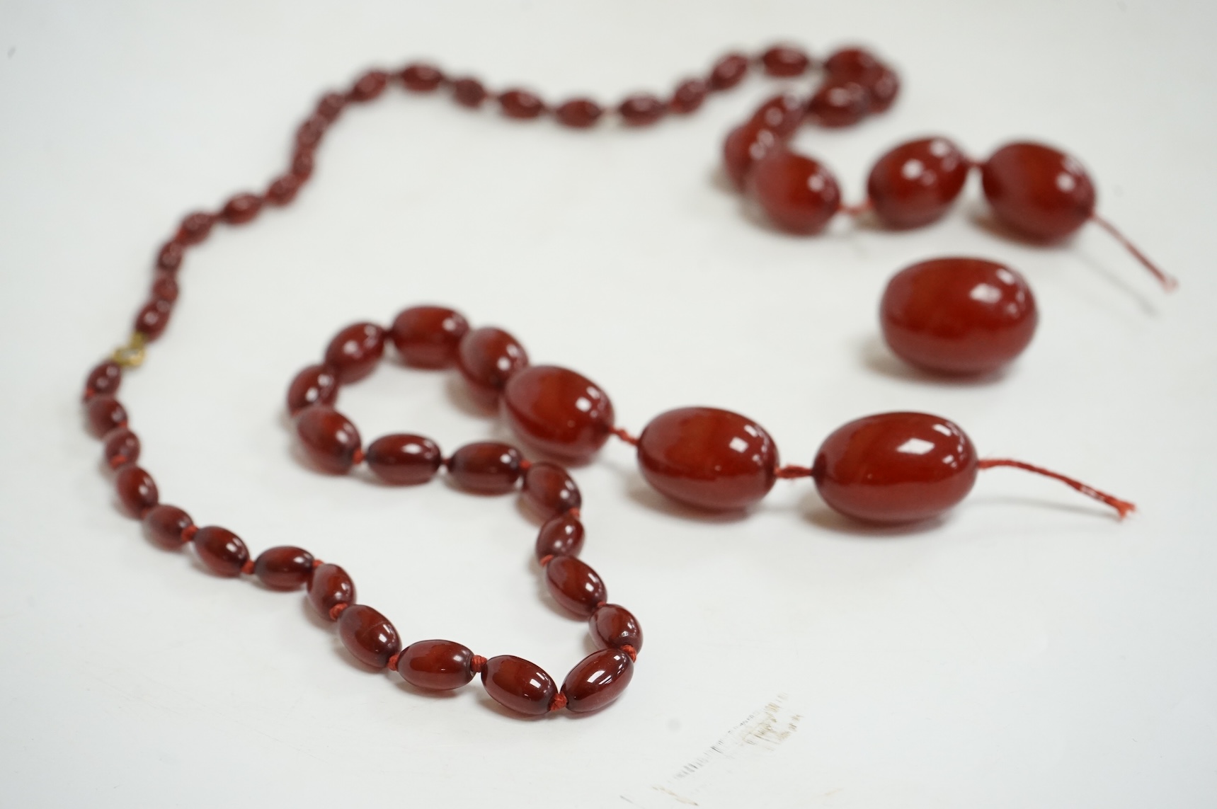 A single strand graduated simulated oval cherry amber bead necklace, string broken, gross weight 73 grams.
